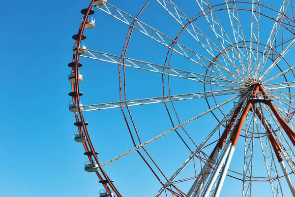 Roda gigante no parque de diversões fotografado contra o sol. Construção da atração com céu rosa e nuvens no fundo. Aventura, conceito de férias, conceitual — Fotografia de Stock