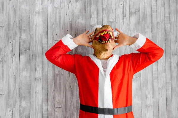 Dinosaurier Verkleidet Als Weihnachtsmann Mit Den Händen Auf Dem Kopf Stockfoto