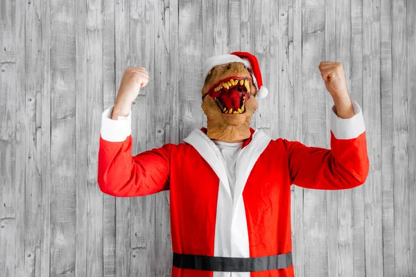 Dinosaurier Als Weihnachtsmann Verkleidet Mit Erhobenen Armen Macht Die Siegergeste lizenzfreie Stockfotos