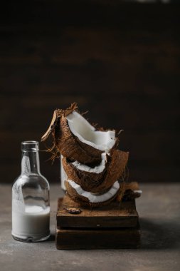 Tahta tahtaların üzerindeki cam şişede hindistan cevizi sütü ve süt damlaları var.