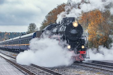 Retro buhar treni sonbahar sabahı istasyondan ayrılıyor..