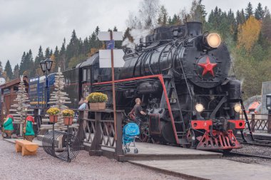 Ruskeala, Rusya - 01 Ekim 2021: Retro buhar treni Sortavala 'dan istasyona ahşap platforma bulutlu bir sonbahar akşamı varır..