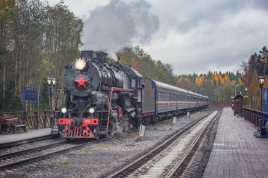 Ruskeala, Rusya - 01 Ekim 2021: Retro buhar treni bulutlu bir sonbahar gününde Sortavala 'dan istasyona ahşap platforma ulaşır..