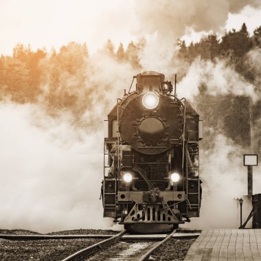 Retro buhar treni gün batımında istasyona ahşap platforma varır..