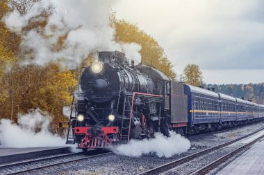Retro buhar treni istasyona ahşap platforma ulaşır. Ruskeala. Rusya.