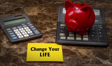 Hayatını değiştir. Hesap makineleri ve kumbaranın arka planında metin var. Finansal başarı kavramı. Seçici odaklanma. Ayarlanmış.