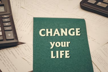 Hayatını değiştir. Hesap makinelerinin arkaplanındaki metin ve bir yığın çek. Finansal başarı kavramı.
