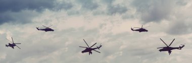 Bulutlu gökyüzünde askeri helikopterlerin siluetleri. Helikopter Uçuşu