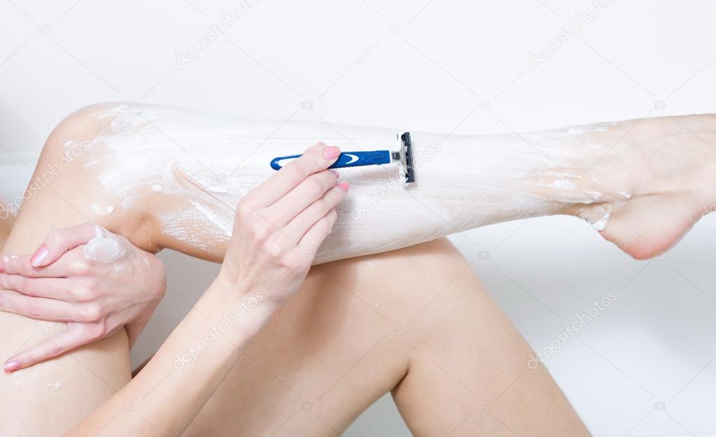 Beautiful woman is shaving her leg