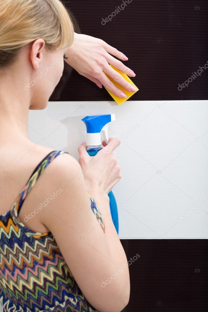 Woman washes a tile with clearing means