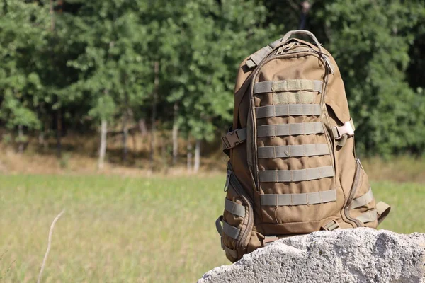 Brown military backpack close-up on the background of nature. Soldier's personal belongings.