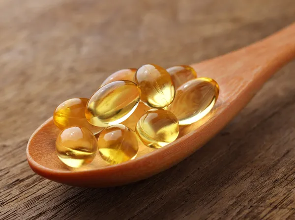 Cápsulas de aceite de pescado en una cuchara — Foto de Stock