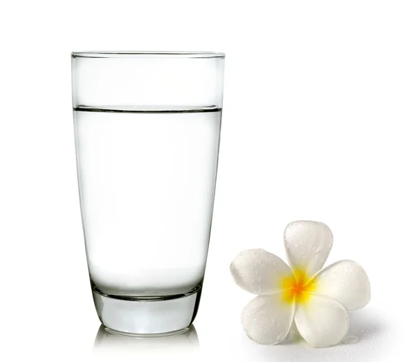 Glas vatten och tropiska blommor frangipani (plumeria) — Stockfoto
