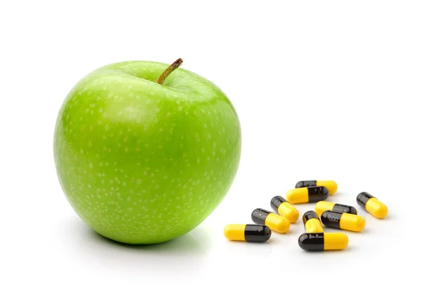 Mela verde e pillole capsule isolate su sfondo bianco — Foto Stock