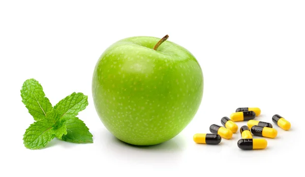 Groene appel geïsoleerd op een witte pagina van munt en pillen capsules — Stockfoto