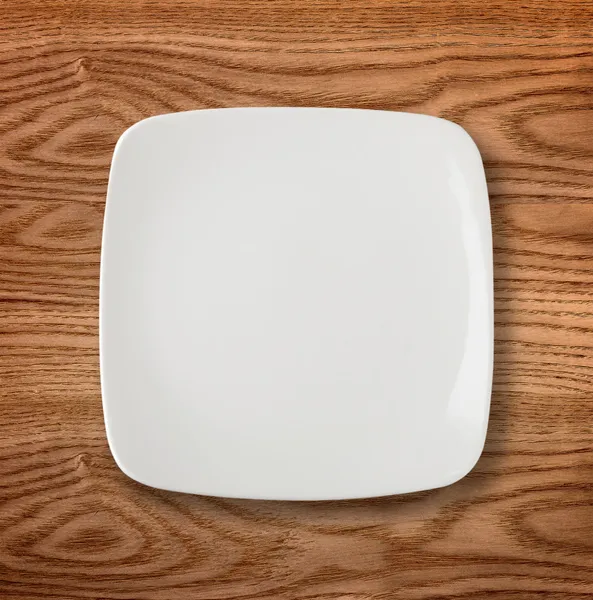 Empty white plate on wooden table — Stock Photo, Image