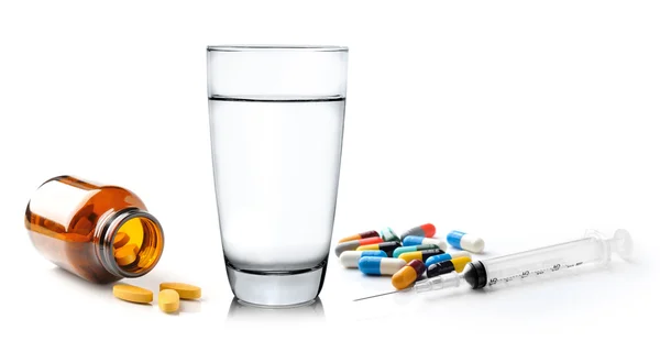 Glas Wasserspritze und bunte Pille und Kapseln auf weiß — Stockfoto