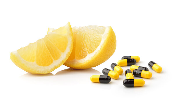 Slice of lemon fruit and pills capsules isolated on white backgr