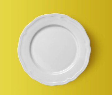 Sarı arka planda beyaz seramik plaka. en üstteki görünüm