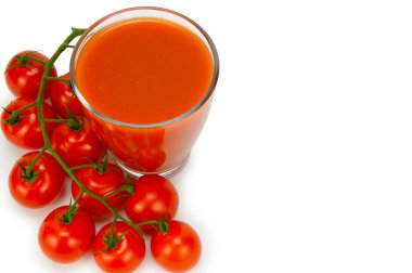 Bir bardak domates suyunun üst görüntüsü. Kapı kolundaki domatesler yakınlarda yatıyor. Beyaz arkaplanda izole.