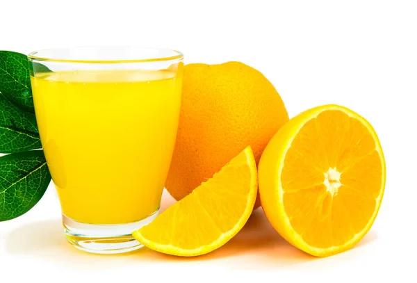オレンジの半分の隣にオレンジジュースのガラスとそれのくさび 緑の葉が後ろに付く — ストック写真