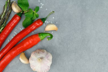Kırmızı biber kabukları, bir baş sarımsak ve birkaç nane yaprağı. Kaba tuz etrafa saçılmış..