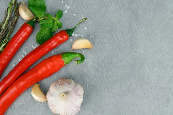 Kırmızı biber kabukları, bir baş sarımsak ve birkaç nane yaprağı. Kaba tuz etrafa saçılmış..