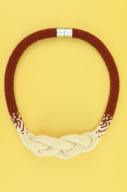 Kadın mücevherleri. Manyetik kapaklı çok renkli boncuklardan örülmüş bir kolye. Sarı arkaplanda izole edilmiş.