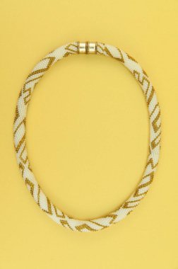 Kadın mücevherleri. Manyetik kapaklı çok renkli boncuklardan örülmüş bir kolye. Sarı arkaplanda izole edilmiş.