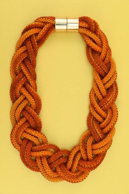 Kadın mücevherleri. Manyetik kapaklı çok renkli boncuklardan örülmüş bir kolye. Sarı arkaplanda izole edilmiş.