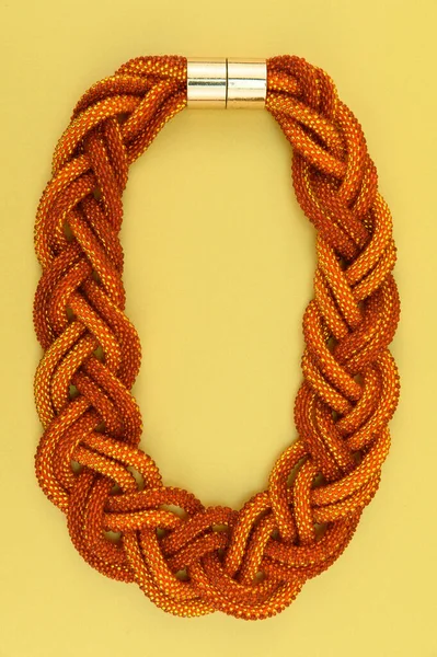 Kadın mücevherleri. Manyetik kapaklı çok renkli boncuklardan örülmüş bir kolye. Sarı arkaplanda izole edilmiş.