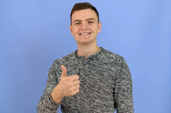 Young Attractive Man Smiles Camera Shows Thumb Image Light Blue — Stock Photo, Image