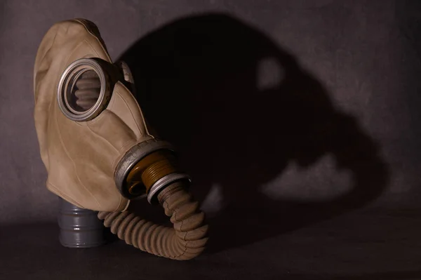 Gas mask with corrugated tube and hard shadow filter box. Image on a dark background.