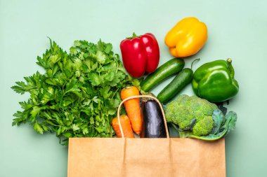Yeşil arka planda izole edilmiş çiğ organik yeşil sebzeli çevre dostu kağıt çanta düz, üst görünüm sıfır atık, plastik serbest konsept