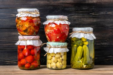 Ev yapımı kiraz domatesleri, salatalıklar, şampiyonlar, sarımsak, patlıcan, kavanozlardaki kırmızı biberler ahşap raflarda ev yapımı konserve ve mayalanmış gıda konsepti mevsimlik ürünler.