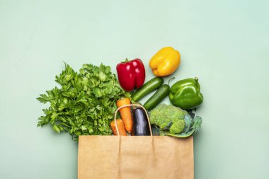 Yeşil arka planda izole edilmiş çiğ organik yeşil sebzeli çevre dostu kağıt çanta düz, üst görünüm sıfır atık, plastik serbest konsept