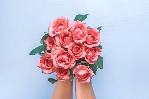 female hands hold romantic bouquet of tender pink roses on pastel blue background Holiday floral card Birthday, Wedding, Happy Valentine\'s, Mother\'s, Teacher\'s day creative concept Top view Flat lay.