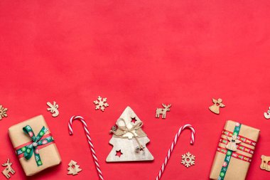 Kırmızı masa üzerinde el yapımı kırmızı, yeşil hediye kutuları kurdeleler, kar taneleri ve numaralarla süslenmiş, Noel süslemeleri ve dekorasyonu kırmızı masa Xmas 'ın gelişen takvim konsepti Top view Düz tatil kartı konsepti.