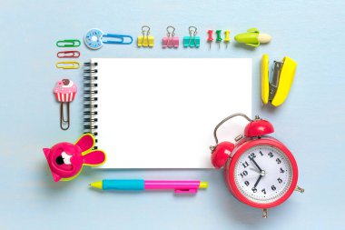 Okula dönmek, eğitim kavramı. Okul malzemelerini içeren sarı sırt çantası - kalemler, hesap makinesi, işaretleyiciler, zımba, not defteri, kağıt raptiyeleri mavi arkaplanda izole edilmiş üst görünüm kopyalama alanı düz bileşimi.