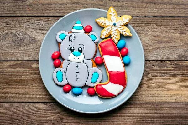 Gingerbread cookies decorated with glaze in shape of bear in hat, lollipop, snowflakes on plate on red background Top view Flat lay Christmas treats, sweets concept New year party Holiday card — Stock Photo, Image
