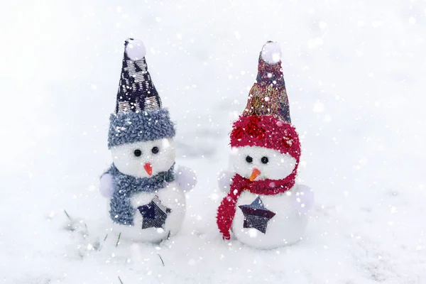 Vrolijk kerstfeest en gelukkig nieuwjaar wenskaart met kopieerruimte Gelukkige twee kleine sneeuwpoppen in rood, blauwe pet en sjaal staan in de winter sneeuw achtergrond Kerstsprookje Hallo januari, Februari concept — Stockfoto