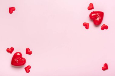 Kalp şeklinde bir çerçeve, pembe arkaplan üzerinde kırmızı kalpler düzeni. Üst görünümde düz bir tatil kartı uzanıyor. Sevgililer günün kutlu olsun, aşk konsepti..
