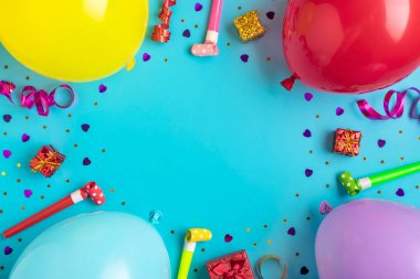 Parti konfetileri, balonlar, flamalar, pokerler ve mavi arka planda süslemelerle dolu kırmızı hediye kutusu olan renkli bir parti çerçevesi. Tatil kartı düz yatıyordu Üst görünüm Mutlu yıllar parti konsepti.