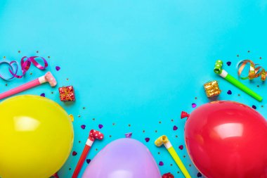 Parti konfetileri, balonlar, flamalar, pokerler ve mavi arka planda süslemelerle dolu kırmızı hediye kutusu olan renkli bir parti çerçevesi. Tatil kartı düz yatıyordu Üst görünüm Mutlu yıllar parti konsepti.
