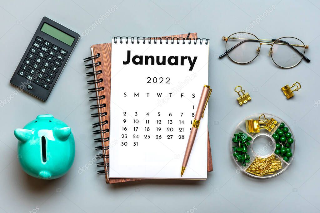 Open calendar January 2022, piggy bank, calculator, pen on gray background Top view Flat lay Education, goals, resolutions, plan, small owner business concept Home workplace