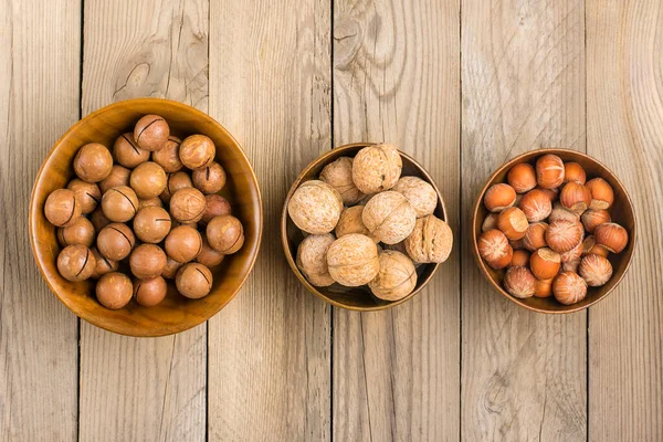 natural organic macadamia, walnut, hazelnut nuts in wooden bowl on wooden background Flat lay Top view Healthy snack Nuts with essential oil rich in vitamins B, PP, lot of fats and high in calories Superfood.