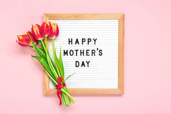 Доска из войлока с текстом С Днем Матери, букет из красных тюльпанов на розовом фоне Открытка на праздничном фоне.