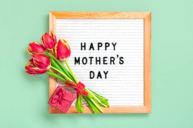 Felt board with text Happy Mothers day, red tulips bouquet on green background greeting holiday card Flat lay Top view