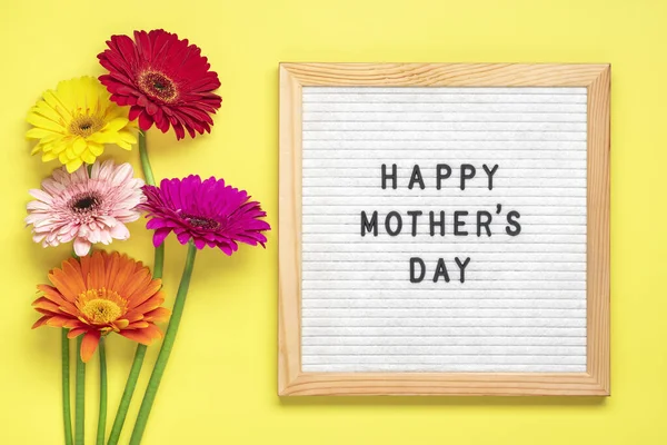 Mutlu Anneler Günleri, sarı arka plan tebrik kartında renkli gerberalar, düz bir manzara..