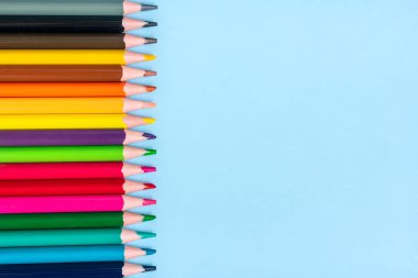 Mavi zemin üzerinde izole edilmiş renkli kalemler dizisi Üst görünüm Düz Eğitim, zanaat konsepti.